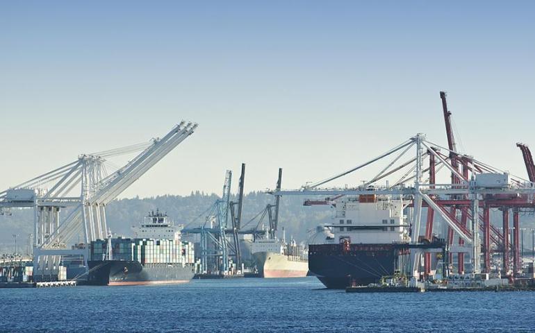 A busy commercial port with large container ships docked at the terminals.