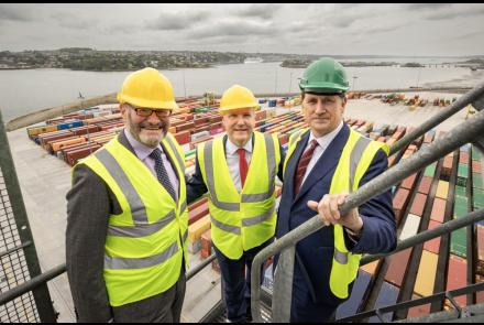 Three men, including TD Eamon Ryan, Michael McGrath TD, stand at Port of Cork