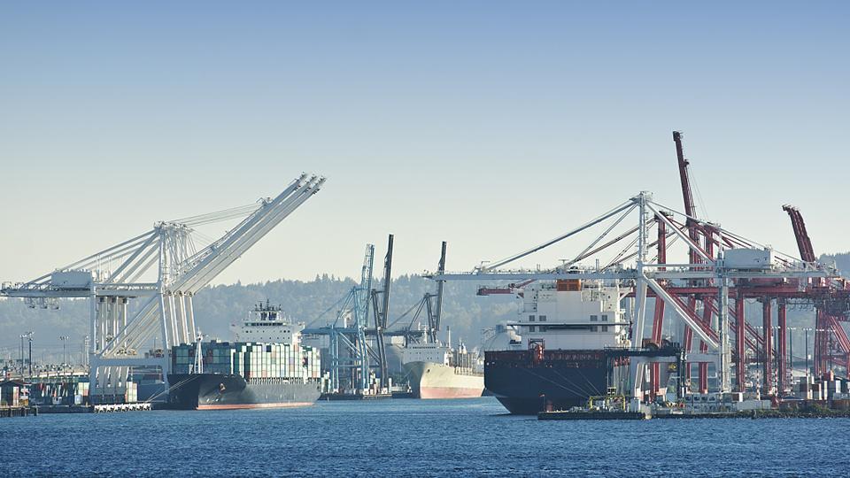 A busy commercial port with large container ships docked at the terminals.